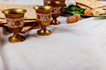 Passover matzoh jewish holiday bread, four glasses kosher wine over table.