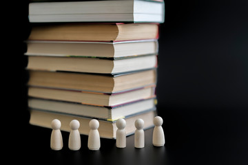 Figures of people and a stack of books on a black background. The concept of education. The problem is not the desire of people to read