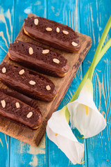 Delicious chocolate and peanut eclairs on a blue wooden table