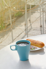 Aromatic coffee in a blue cup with eclairs in a summer cafe.