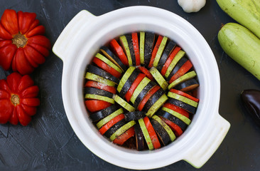 Vegetables for cooking process ratatouilles: zucchini, eggplant and tomatoes are in ceramic form on...