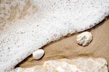 sea wave with bubbles on the sand beach