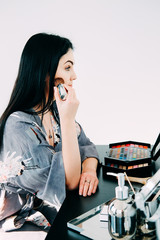 Beautiful brunette with long hair doing her makeup