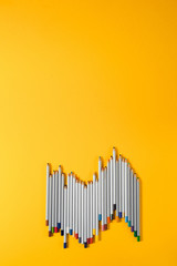 colored pencils arranged in a chaotic line on yellow background