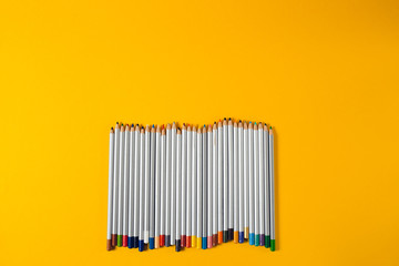 colored pencils arranged in a chaotic line on yellow background