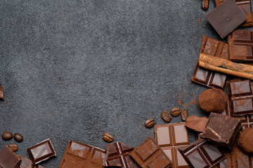 Dark or milk organic chocolate pieces, cocoa powder and truffle candies on dark concrete backgound