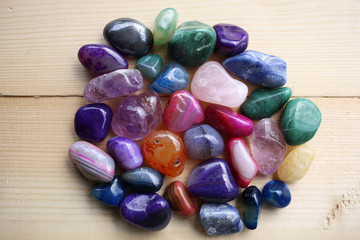 A variety of semi-precious stones of different minerals and structures on a wooden table.