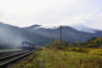 Diesel train on the mountain railway and stunning view  of mountain range in the clouds, Carpathian mountains, Ukraine