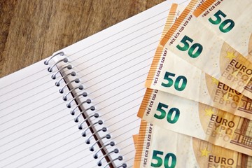 Contabilidad y finanzas, billetes de euro y cuaderno en blanco.