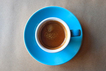 Cup of coffee on wooden table. Espresso shot with crema top angle view.