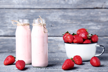 Smoothie in glass bottles with strawberries on grey wooden table