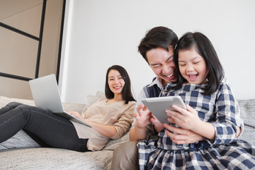 Happy Asian family spending time together at home playing game, tablet for education