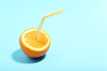 Fototapeta na wymiar Orange fruit with straw on blue background. Minimalism concept