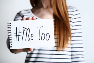 Woman holding notepad with text Me Too on grey background