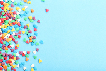 Colorful heart shaped sprinkles on blue background