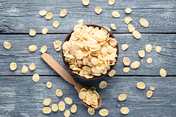 Corn flakes in bowl with spoon on grey wooden table