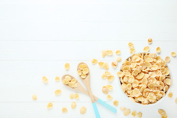 Corn flakes in bowl with spoons on white wooden table