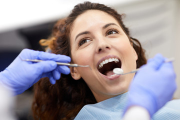 Head and shoulders portrait of beautiful young woman lying in dental chair with mouth open during consultation, copy space