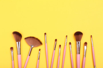 Set of makeup brushes on yellow background