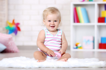 Baby girl with bottle sitting on white carpet