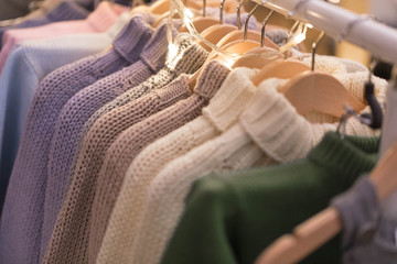 Obraz na płótnie Canvas Hangers with women's and men's wear in shop. Sweaters of large knitting