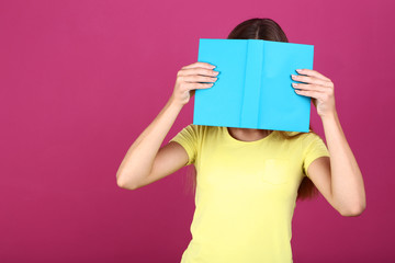 Young girl with book on pink background