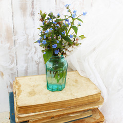 Blue flowers brunners in a glass vase on a white vintage background. Bouquet in retro style.