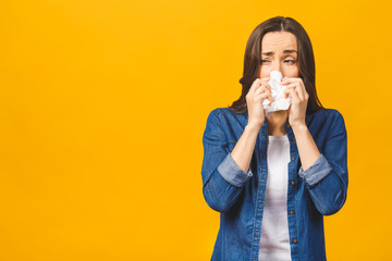 Portrait of young woman coughing with a napkin, catch cold, feeling ill, yellow studio background,...