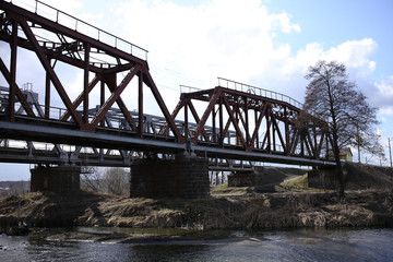Obraz premium Metallic railway bridge over the river with a fast flow.