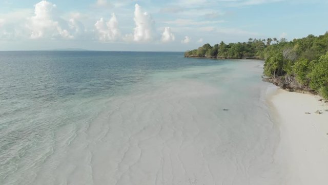Aerial: Flying over tropical beach turquoise water coral reef , Tomia island Wakatobi National Park Indonesia Maldives Polynesia white sand beach. Native cinelike D-log color profile