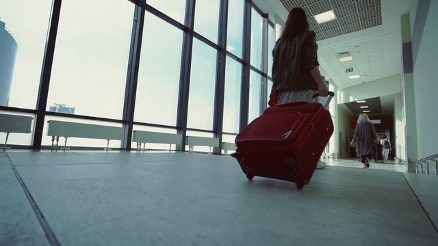Young girl with a red suitcase at the airport