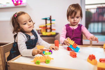 Children toddlers girls play toys at home, kindergarten or nursery.