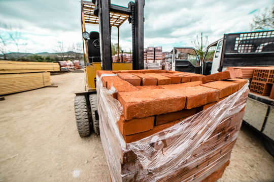 Fork lifter carry construction material clay bricks at the warehouse building site