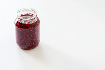 Glass jar with red jam on the table