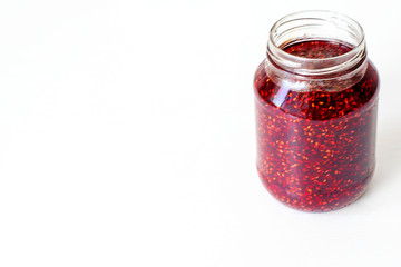 Glass jar with red jam on the table