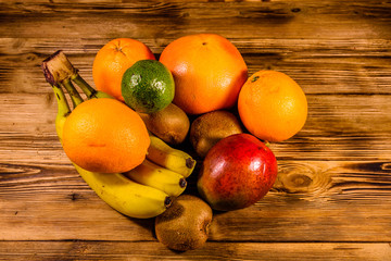 Still life with exotic fruits. Bananas, mango, oranges, avocado, grapefruit and kiwi fruits on wooden table