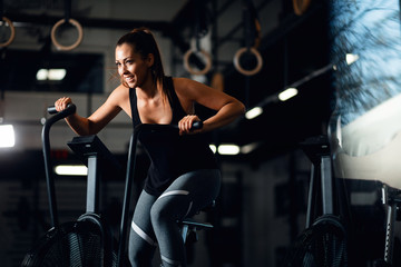 Fototapeta na wymiar Happy athletic woman on exercise bike in a gym.