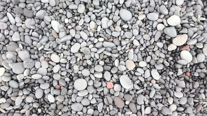 Background with lots of smooth stones on a rocky beach
