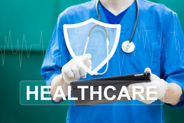 A young doctor is holding a big shield with text healthcare icon security. Medicine and life and health insurance concept.