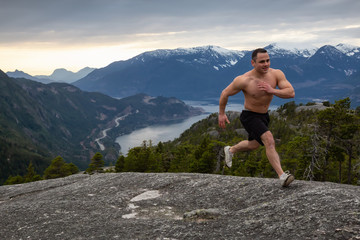 Fit and Muscular Young Man is Running up the Mountain during a cloudy sunset. Taken on Chief Mountain in Squamish, North of Vancouver, BC, Canada.