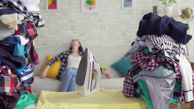 portrait of a tired woman housewife on the background of stacks of clothes