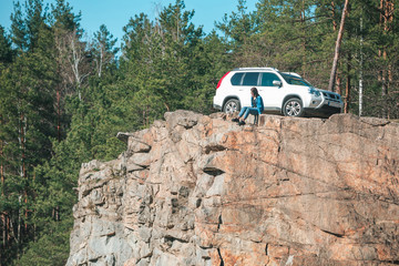 Fototapeta na wymiar woman sitting on cliff with beautiful view at sunny day. suv car at background