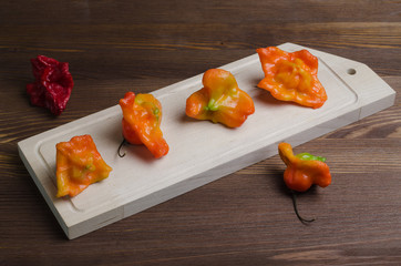Colorful peppers unusual shape on a light cutting Board, on a dark wooden table.