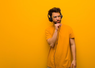 Young man listening to music doubting and confused