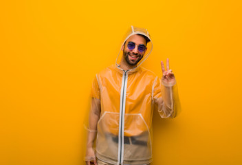 Young man wearing a rain coat doing a gesture of victory
