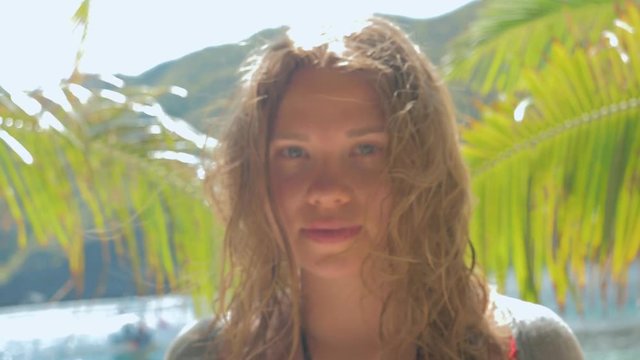 Slow motion close-up gimbal shot of beautiful european young woman on tropical beach looking in the camera