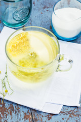 Fresh chamomile tea in a glass cup on a wooden table, chamomile blossoms in a cup, healthcare and healthy eating concept
