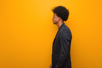 Obraz premium Young business african american man over an orange wall on the side looking to front