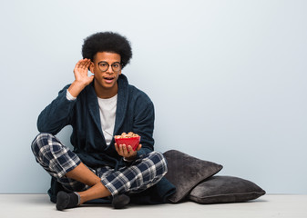 Young black man sitting and having a breakfast try to listening a gossip