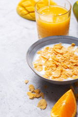 Breakfast which consist of different yellow ingredients - sereales and fruits. Gray background
